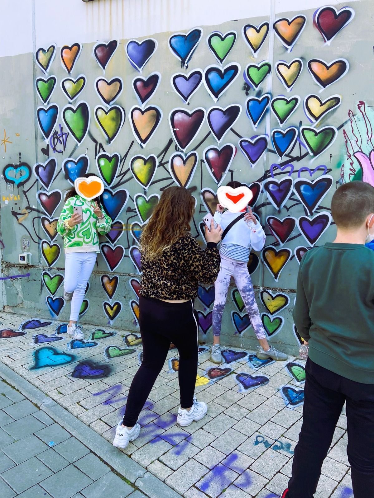 ילדים מצטלמים מול קיר מלא לבבות צבעוניים